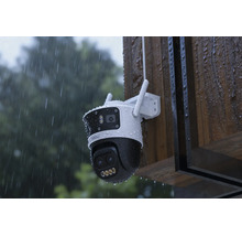 Caméra de surveillance résistante aux intempéries avec deux objectifs, montée sur un mur en bois sous la pluie.