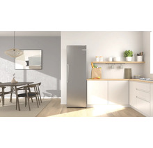 Réfrigérateur moderne en acier inoxydable dans une cuisine lumineuse et rangée avec coin repas, meubles en bois et placards blancs.