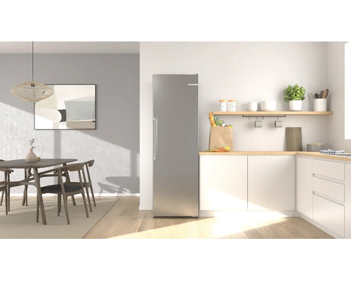 Réfrigérateur moderne en acier inoxydable dans une cuisine lumineuse et rangée avec coin repas, meubles en bois et placards blancs.