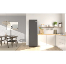 Cuisine moderne et lumineuse avec un réfrigérateur posable, des armoires, un plan de travail en bois et un coin repas avec table.