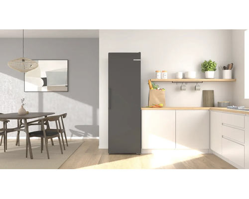 Cuisine moderne et lumineuse avec un réfrigérateur posable, des armoires, un plan de travail en bois et un coin repas avec table.