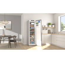 Congélateur armoire ouvert rempli d'aliments dans une cuisine moderne et lumineuse avec coin repas.