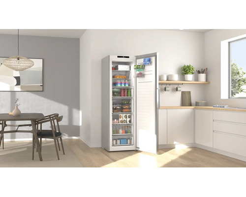 Congélateur armoire ouvert rempli d'aliments dans une cuisine moderne et lumineuse avec coin repas.
