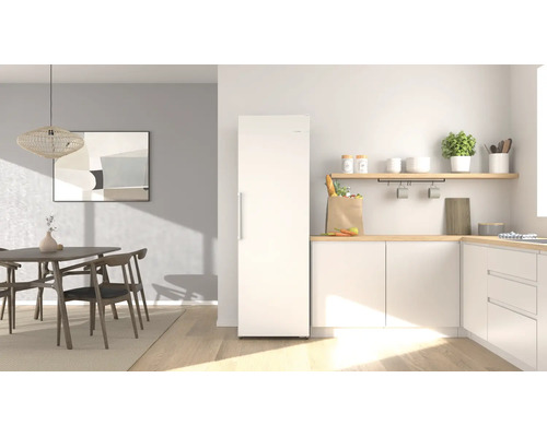 Cuisine moderne et lumineuse avec un réfrigérateur blanc indépendant, des plans de travail en bois et un coin repas avec des meubles en bois.