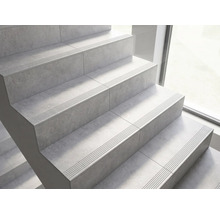 Escalier avec carrelage aspect pierre et rainures antidérapantes sur les marches.