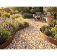 Allée de jardin en gravier avec bordure de massif courbe en métal aspect rouille, plantée de lavande, d'herbes ornementales et de succulentes.