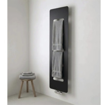 Radiateur panneau noir moderne avec porte-serviettes intégré dans une salle de bain lumineuse avec tabouret en bois et serviettes.