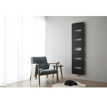 Radiateur design noir sur un mur gris dans un salon lumineux avec fauteuil, table d'appoint et tapis blanc.