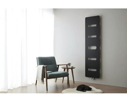 Radiateur design noir sur un mur gris dans un salon lumineux avec fauteuil, table d'appoint et tapis blanc.