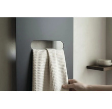 Radiateur plat gris foncé avec découpe horizontale servant de porte-serviettes et une serviette claire à structure gaufrée.