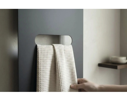 Radiateur plat gris foncé avec découpe horizontale servant de porte-serviettes et une serviette claire à structure gaufrée.