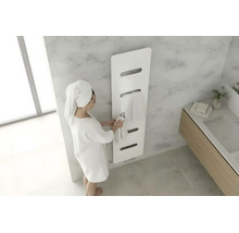 Sèche-serviettes moderne blanc dans une salle de bains lumineuse avec aspect marbre et une personne en peignoir.