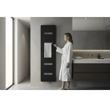 Salle de bain moderne avec radiateur design noir au mur, une femme en peignoir blanc et un meuble sous-vasque foncé.