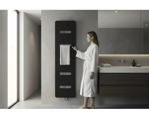 Salle de bain moderne avec radiateur design noir au mur, une femme en peignoir blanc et un meuble sous-vasque foncé.