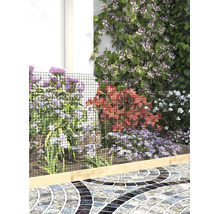 Grillage servant de bordure de jardin avec diverses fleurs et un chemin en mosaïque.