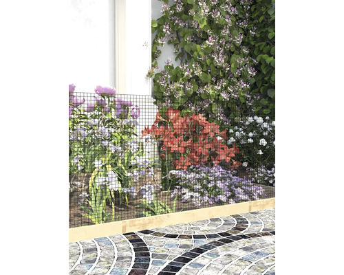 Grillage servant de bordure de jardin avec diverses fleurs et un chemin en mosaïque.
