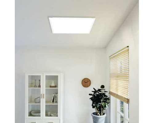 Panneau LED carré au plafond dans une pièce lumineuse au mobilier moderne avec vitrine, horloge murale et plante.