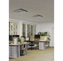 Bureau moderne avec deux plafonniers LED carrés noirs à grille, bureaux en bois et chaises ergonomiques dans un espace de travail lumineux.