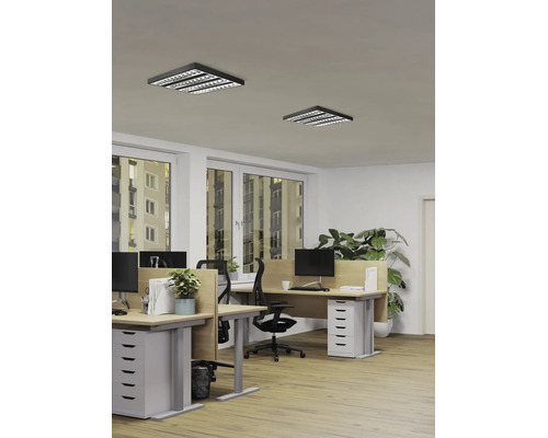 Bureau moderne avec deux plafonniers LED carrés noirs à grille, bureaux en bois et chaises ergonomiques dans un espace de travail lumineux.