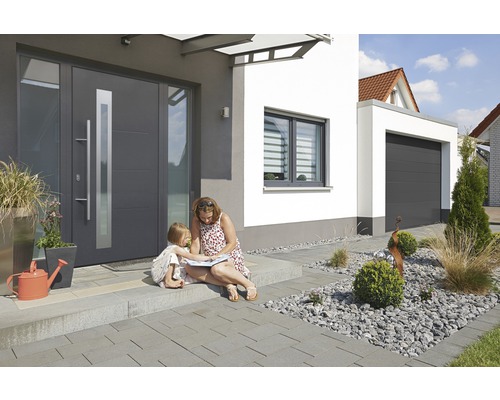 Maison moderne avec porte d''entrée, fenêtre et garage, mère et enfant assis devant.