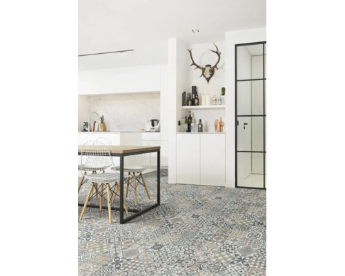 Cuisine moderne lumineuse avec carrelage de sol motif patchwork, table en bois avec cadre en métal noir et chaises en fil de fer blanc.