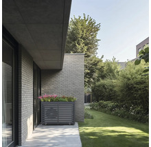 Habillage moderne pour climatiseur ou pompe à chaleur en métal gris avec jardinière intégrée contre un mur en briques dans un jardin.