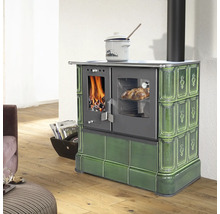 Cuisinière à bois en céramique verte avec fenêtres pour feu et four dans une pièce lumineuse avec parquet.