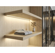 Étagère murale en bois clair avec éclairage LED intégré dans un dressing, design moderne.