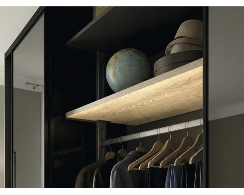 Vue intérieure d une armoire avec étagère en bois éclairée, tringle à vêtements et cintres en bois.