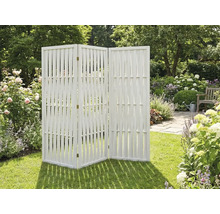 Paravent de jardin en bois blanc à trois panneaux sur une pelouse au milieu d'un jardin fleuri.
