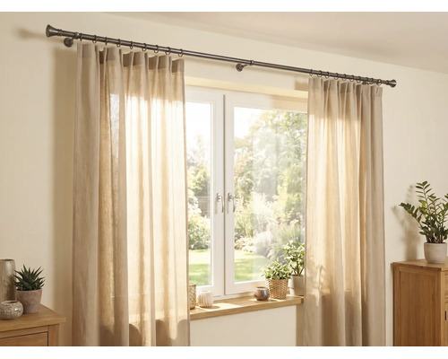 Scène lumineuse avec une tringle à rideaux en métal foncé au-dessus d'une fenêtre, rideaux beiges semi-transparents et plantes d'intérieur.