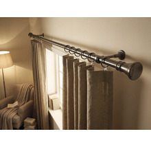 Tringle à rideaux en métal avec anneaux et rideaux en tissu dans une pièce lumineuse avec fenêtre et fauteuil.