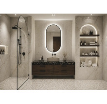 Salle de bains moderne avec murs en marbre, douche à l'italienne, meuble sous-vasque sombre, miroir ovale rétroéclairé et niche éclairée.