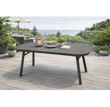 Table de jardin ovale moderne sur une terrasse en bois. La table sombre est décorée avec une lanterne, un bol de fruits et une plante.