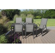 Salon de jardin composé d'une table sombre et de cinq chaises grises sur une terrasse en bois dans un jardin lumineux et organisé.