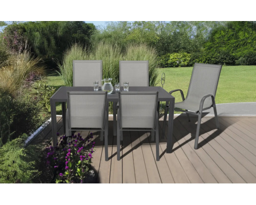 Salon de jardin composé d'une table sombre et de cinq chaises grises sur une terrasse en bois dans un jardin lumineux et organisé.