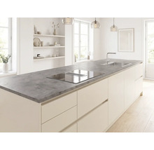 Îlot de cuisine moderne avec plan de travail gris aspect pierre, plaque de cuisson intégrée avec hotte aspirante et évier dans une pièce lumineuse.