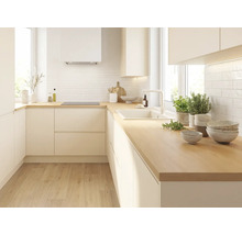 Cuisine moderne en L avec façades sans poignées claires, plan de travail en bois, crédence blanche, évier et plaque à induction.
