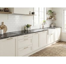 Cuisine lumineuse avec façades blanches de style campagnard, plan de travail foncé aspect marbre, crédence en carrelage blanc et étagères.