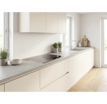 Cuisine moderne lumineuse avec façades crème, plan de travail gris aspect béton, plaque à induction et évier en inox.