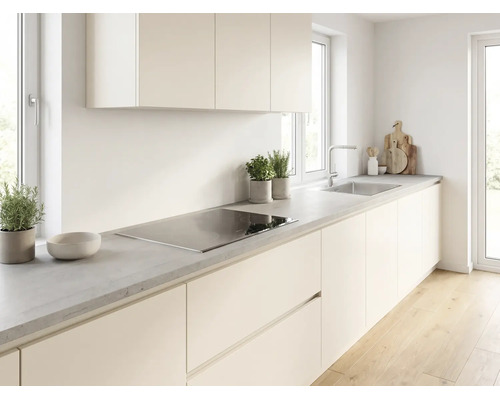 Cuisine moderne lumineuse avec façades crème, plan de travail gris aspect béton, plaque à induction et évier en inox.