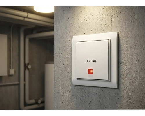 Weißer Heizungsschalter mit Aufdruck Heizung und roter Kontrollleuchte an einer Betonwand im Keller.