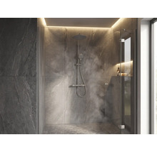 Douche à l italienne moderne avec carrelage mural aspect pierre, pommeau de douche à effet pluie, paroi en verre et éclairage indirect.