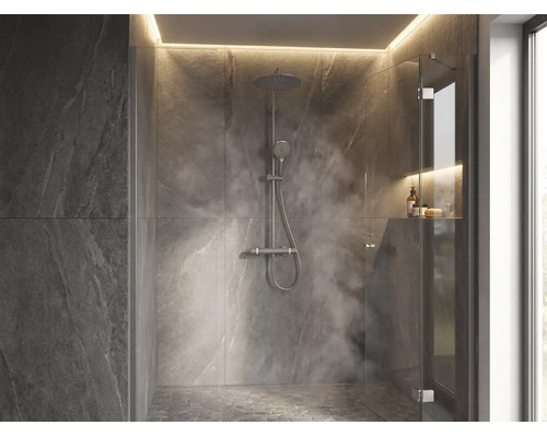 Douche à l italienne moderne avec carrelage mural aspect pierre, pommeau de douche à effet pluie, paroi en verre et éclairage indirect.