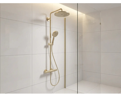 Duschsystem in Goldoptik mit Regendusche, Handbrause und Thermostatarmatur in einer hell gefliesten Dusche mit Glastrennwand.