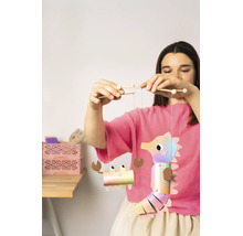 Une femme tient un mobile de bricolage en papier avec un hippocampe et un crabe attachés à des bâtonnets en bois.