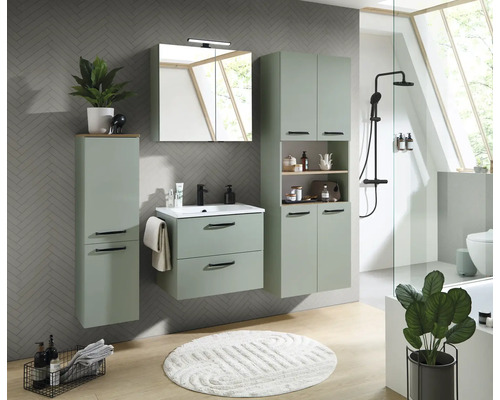 Ensemble de meubles de salle de bain vert sauge avec meuble sous vasque, armoire de toilette et colonnes sur un mur gris à motifs chevrons.