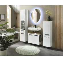 Salle de bains moderne avec meubles blancs, lavabo, miroir ovale éclairé, colonne de rangement et baignoire.