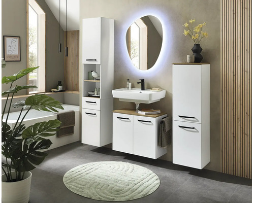 Salle de bains moderne avec meubles blancs, lavabo, miroir ovale éclairé, colonne de rangement et baignoire.
