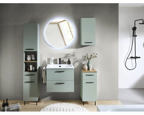 Ensemble de meubles de salle de bains vert sauge avec lavabo, miroir LED rond, colonne et meubles d'appoint sur mur à motif chevrons.